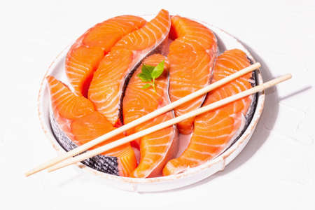 Fresh raw salmon or trout fish fillet steaks. Minimalistic design, modern hard light, dark shadow. Chilled ingredients for cooking healthy seafood. White putty culinary background, copy spaceの写真素材