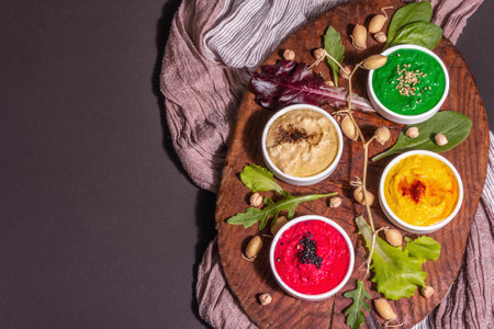 Colorful hummus bowls, healthy vegan dips. Traditional Middle Eastern food. Beets, spinach, aromatic spices. Black stone concrete background, top viewの写真素材