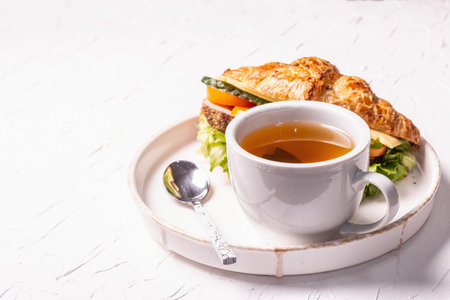 Healthy breakfast concept. Morning good mood with tea and croissant. White putty background, copy...