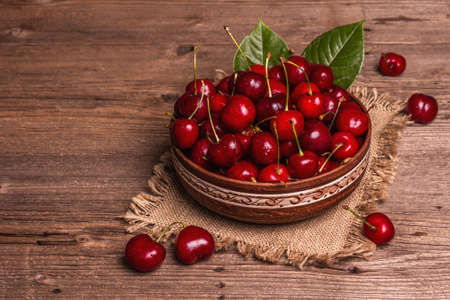 Fresh ripe sweet cherries in a bowl with droplets of water. Dark rustic wooden background, copy spaceの写真素材