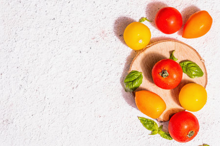 Assortment ripe tomatoes with fresh basil leaves. New harvest, whole and cut in half vegetables, trendy hard light, dark shadows. White putty background, top viewの写真素材