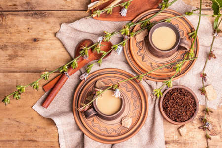Hot natural chicory caffeine free drink in ceramic cups on a wooden table. Healthy alternative replacement for coffee, caffeine. Blue chicory flowers, fresh roots, top viewの写真素材