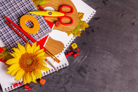 School supplies on a black chalkboard background. Composition with album, notebook, palette,...