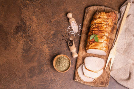 Homemade baked pork tenderloin on stone concrete background. Whole roasted piece, cut slices with spices, flat lay, top viewの写真素材