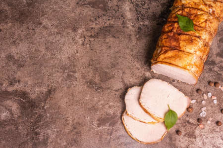 Sliced baked pork loin on a stone concrete background. A trendy hard light, dark shadow, spices and herbs, copy spaceの写真素材