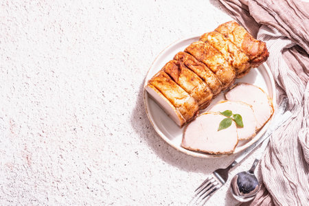 Baked pork loin on a ceramic stand with cutlery. A trendy hard light, dark shadow, white putty background, top viewの写真素材