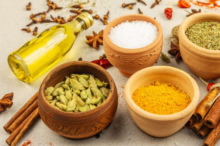 A set of spices for cooking curry. Aromatic condiments: turmeric, paprika, cardamom, cinnamon, star anise, chili, black pepper, dry herbs, salt. Light stone concrete background, close upの写真素材