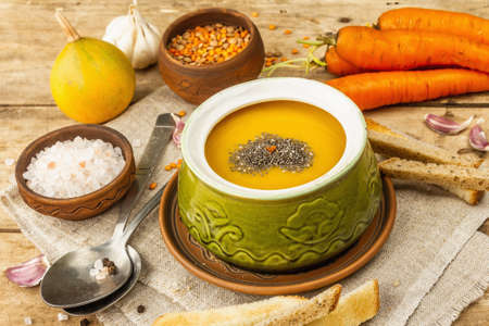 Vegetable cream soup. Traditional autumn hot food, croutons, and spices. Wooden boards background, close upの写真素材