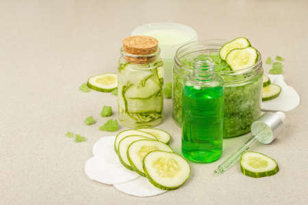 Homemade cosmetics with cucumber. Detoxification skin vegetable masks. Natural cream, sea salt, face lotion, and tonic water. Light stone concrete background, copy spaceの写真素材