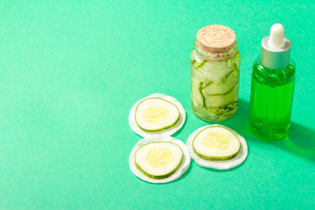 Homemade cucumber cosmetics. Detoxification skin vegetable masks. Natural face lotion, and tonic water. Trendy hard light, dark shadow, turquoise background, copy spaceの写真素材