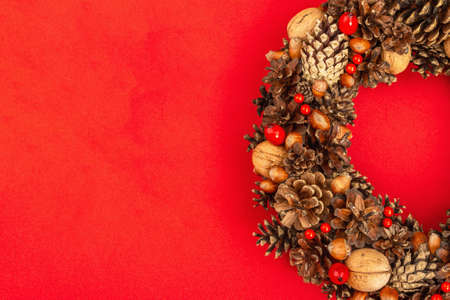 Autumn wreath of cones, nuts, and berries. Creative composition, the handmade. Home decoration festive concept. Red pastel background, top viewの写真素材