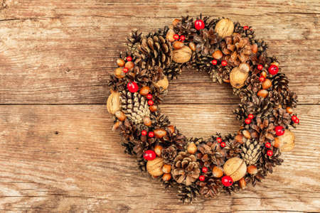 Autumn wreath of cones, nuts, and berries. Creative composition, the handmade. Home decoration festive concept, old wooden background, top viewの写真素材