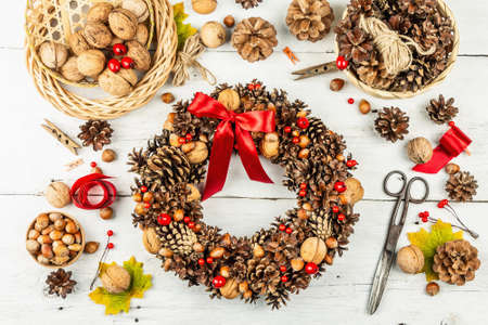 Autumn wreath of cones, nuts, and berries. Assortment from natural materials for creative composition. Handmade home decoration festive concept. White wooden background, top viewの写真素材
