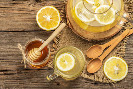 Hot ginger tea with lemon and honey in a glass cup on a wooden boards background. Alternative medicine, natural home remedy for cold and flu, top viewの写真素材