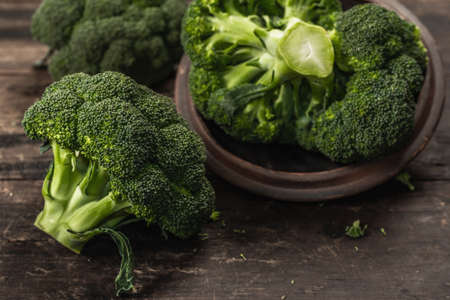 Green fresh broccoli on old wooden background. Ripe vegetables for diet and healthy eating, organic food. Flat lay, macro photo, selective focus, close upの写真素材