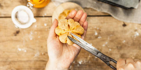 Pumpkin buns or biscuits, traditional fall baked goods. Female hands hold cookies. Seasonal homemade food and autumn decor. Old wooden boards background, top viewの写真素材