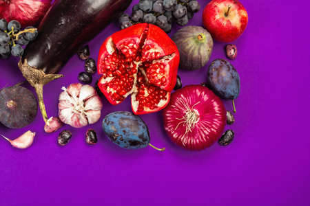 Blue, red and purple food. Culinary background of fruits and vegetables. Fresh figs, plums, onion, eggplant, grapes, cabbage, apple, garlic, dogwood, pomegranate, beetroot. Violet background, flat layの写真素材