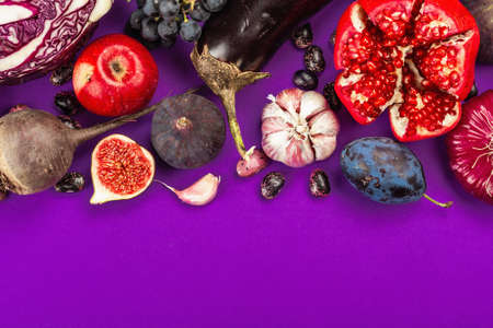 Blue, red and purple food. Culinary background of fruits and vegetables. Fresh figs, plums, onion, eggplant, grapes, cabbage, apple, garlic, dogwood, pomegranate, beetroot. Violet background, flat layの写真素材