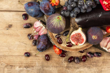 Blue, red and purple food. Culinary background of fruits and vegetables. Fresh figs, plums, onion, eggplant, grape, cabbage, apple, garlic, dogwood, pomegranate, beetroot. Wooden stands and old boardsの写真素材