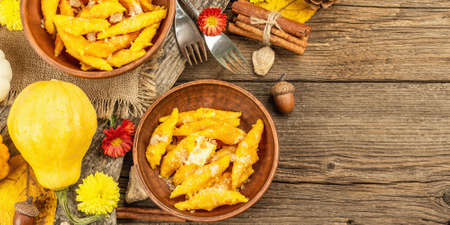 Pumpkin gnocchi or Italian dumplings. Healthy vegetarian squash dish with cottage cheese. Autumn decor with fall leaves, cones, ripe whole pumpkins, flowers and spices. Old wooden background, bannerの写真素材