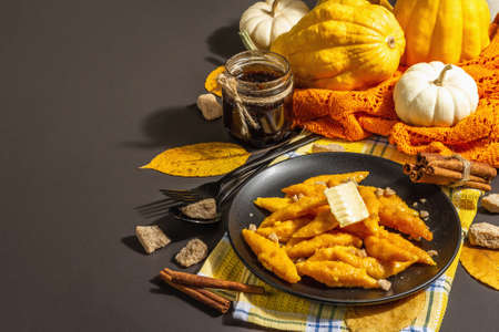 Lazy pumpkin dumplings, gnocchi with butter and brown sugar. Warm autumn dish, sweet healthy food. Black stone concrete background, trendy hard light, dark shadow, copy spaceの写真素材