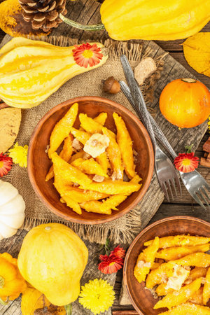 Pumpkin gnocchi or Italian dumplings. Healthy vegetarian squash dish with cottage cheese. Autumn decor with fall leaves, cones, ripe whole pumpkins, flowers and spices. Old wooden background, top viewの写真素材