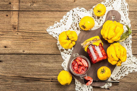 Homemade quince jam in a glass jar. Fresh fruits, sweet marmalade, vintage arrangement. Old wooden background, top viewの写真素材