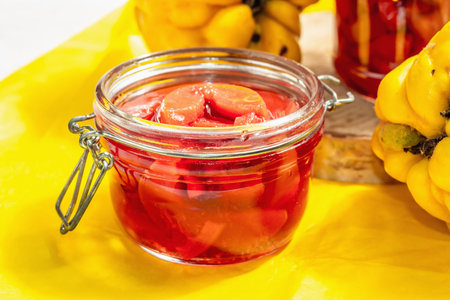 Ripe whole quince and sweet jam from it. Fresh fruit, an essential ingredient for a healthy diet, dessert in a glass jar. Trendy hard light, dark shadow. White wooden background, close upの写真素材