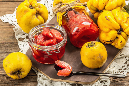 Homemade quince jam in a glass jar. Fresh fruits, sweet marmalade, vintage arrangement. Old wooden...