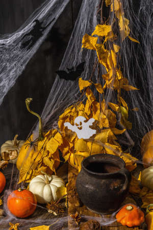 Halloween background. Pumpkins, spiders, cobwebs, bat, ghost. Festive symbols, autumn leaves, witch's pot of potions. The atmospheric arrangement, black backgroundの写真素材