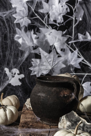 Halloween composition with witch's pot, pumpkins, bat, ghost, spider, and cobwebs. Black-white tones, festive spiritの写真素材