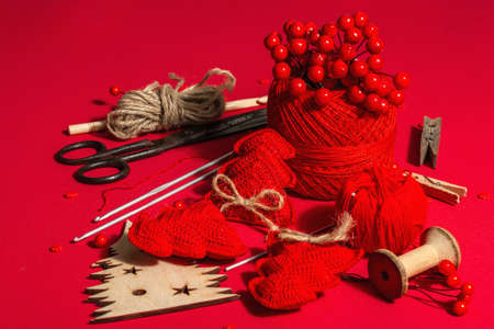 Festive handmade concept. Threads, crochet hooks, vintage scissors, New Year's or Christmas decor. Objects in red colors, monochrome background, close upの写真素材