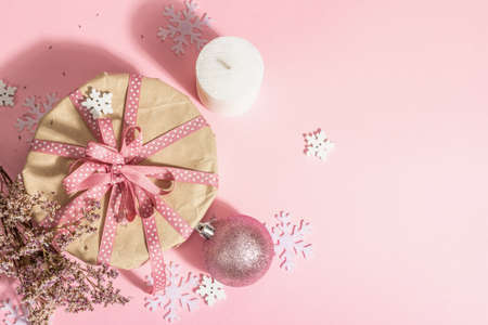 Christmas or New Year gift concept in pink tones. Wrapper box, tied bow, dry flowers, and festive toy. Zero Waste style, trendy hard light, dark shadow, rosy background, top viewの写真素材