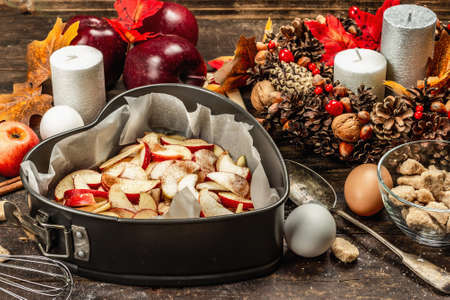 Apple charlotte is ready to bake. Kitchen utensil, set of ingredients, seasonal decor. Cooking sweet pastries with spices. Old wooden background, copy spaceの写真素材