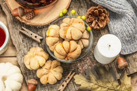 Autumn tea concept. Cookies with pumpkin puree, black tea in a glass teapot, fall decor. Wreath,...