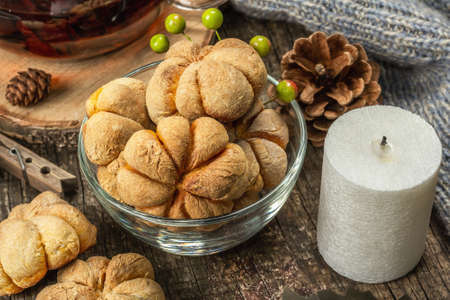 Autumn tea concept. Cookies with pumpkin puree, black tea in a glass teapot, fall decor. Wreath,...