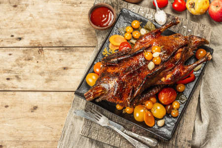 Whole roast duck stuffed with apples. Poultry served with pickled vegetables. A festive dish for Christmas, Thanksgiving Day, or any holiday. Wooden background, cutlery, top viewの写真素材