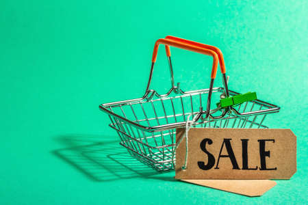 Empty shopping basket isolated on turquoise background. Black Friday or Christmas Sale concept. A trendy hard light, dark shadow. Flat lay, mockup, template, copy spaceの写真素材