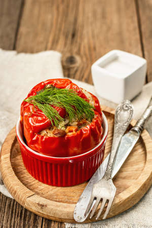 Homemade meat and rice stuffed bell peppers. Olive oil, sauce, cutlery. Traditional healthy food, vintage wooden background, close up, selective focusの写真素材