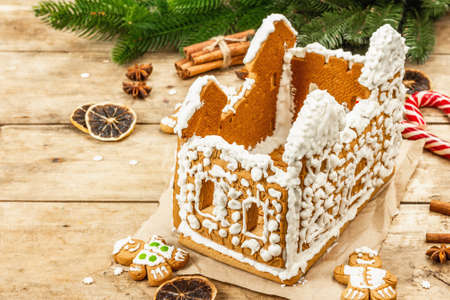 Gingerbread House decorated by sweet icing. Handmade process, festive New Year decor. Traditional...