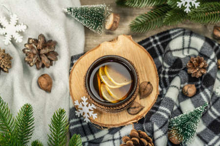 Hot black tea and lemon with winter decor. Cozy sweater, fir tree branches, nuts, snowflakes. Festive seasonal arrangement, good mood concept, rustic style, top viewの写真素材