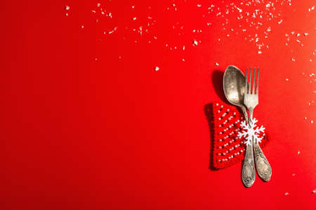 Christmas table setting in red tones with vintage cutlery. Festive New Year decor, card template. Modern hard light, dark shadow. Flat lay, red background, top viewの写真素材