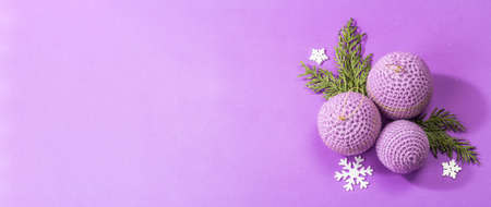 Crocheted Christmas balls and festive New Year decor in a fashion lilac very peri color. Winter greeting card, trendy hard light, dark shadow. Violet matte background, banner formatの写真素材