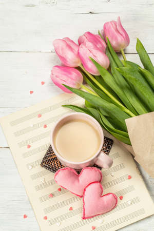 Romantic flat lay composition with a cup of coffee, soft felt hearts, and fresh tulips. Valentines or Mother's Day, Wedding, good morning concept. White wooden background, top viewの写真素材