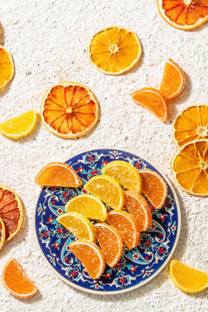 Lemon and orange marmalade. Jelly candies in the form of slices. Traditional Turkish pattern, trendy hard light, dark shadow. Putty background, food's flat lay, top viewの写真素材