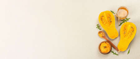 Halves of raw pumpkin with butternut squash puree, honey and fresh herbs. Assortment ingredients for cooking, stone concrete background, banner formatの写真素材