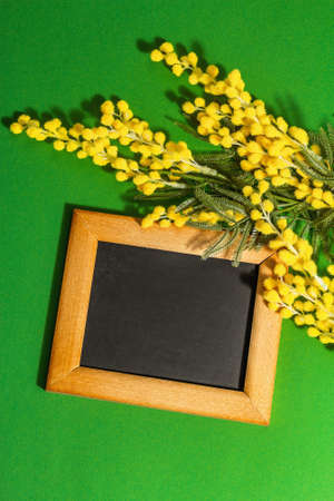 Mimosa flowers background with wooden frame. Festive spring concept, Easter, Women Day, flat lay, top viewの写真素材
