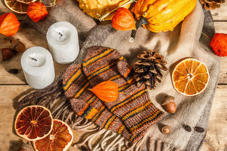 Autumn cozy composition. Scarf, warm mittens, candles, pumpkins, fall decor. Wooden rustic...
