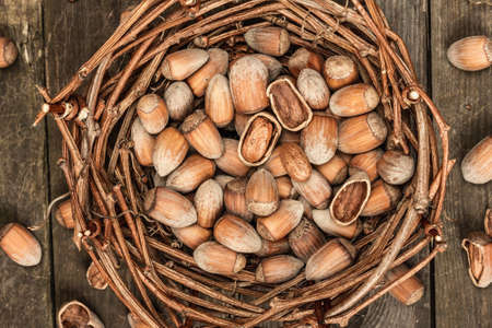 Ripe hazelnuts in shells. Harvest in a wicker basket, a healthy ingredient for snacks. Old wooden background, top viewの写真素材