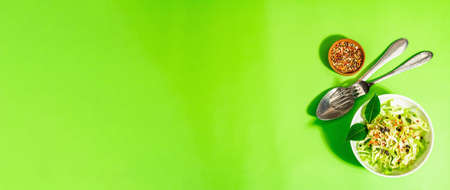 spring diet salad. Fresh vegan vitamin food. Sliced cabbage, spices, olive oil, dry berries. Healthy lifestyle concept. Trendy hard light, dark shadow, bright green background, banner formatの写真素材